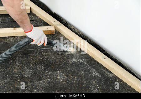 Worker cleans the dust on the floor using a vacuum cleaner. Stock Photo