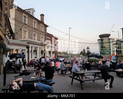 People enjoying the warm spring evening of the May Bank Holiday outside The Flag pub, Watford, UK drinking and socialising as the sun goes down. Stock Photo