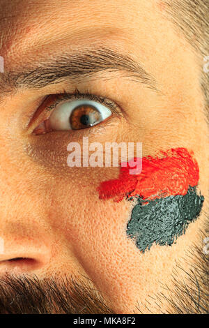 Portrait of a man with the flag of the Germany painted on him face. Stock Photo