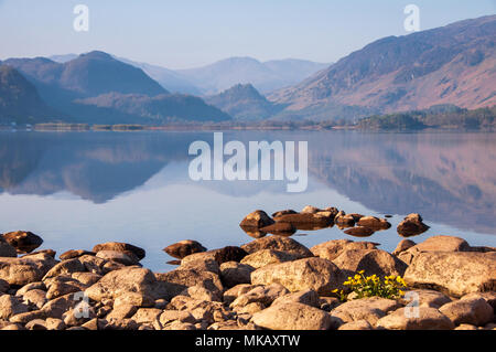 Soft morning light illuminates the Jaws of Borrowdale mountains, reflected in the calm waters of Derwent Water in the English Lake District. Stock Photo