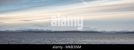 The mountains of Cumbria's Lake District rise behind the waters of Morecambe Bay in the Irish Sea, viewed from Morecambe in Lancashire. Stock Photo