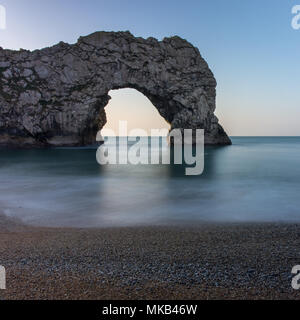 Early morning light shines through the natural limestone arch at Durdle Door on England's Jurassic Coast.