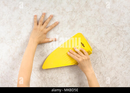 hands with scraper smoothing wallpaper on the wall Stock Photo