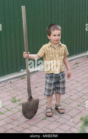 Little boy with a big shovel. little happy boy working with shovel in garden. boy 5 years old keeping a big shovel. Stock Photo