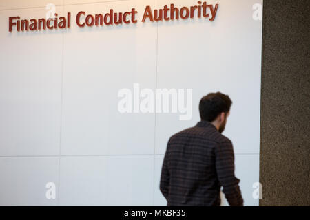 Financial Conduct Authority (FCA) offices, North Colonnade, Docklands, London. Reception showing corporate logo with employees entering through securi Stock Photo