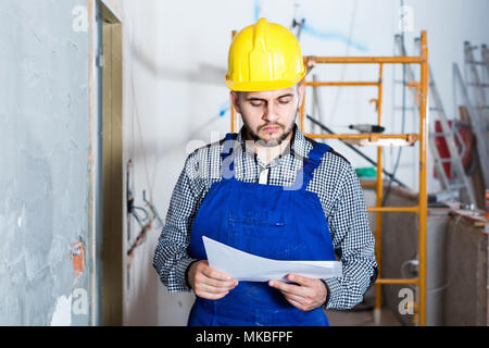Diligent  builder is looking on the project of work for the object. Stock Photo