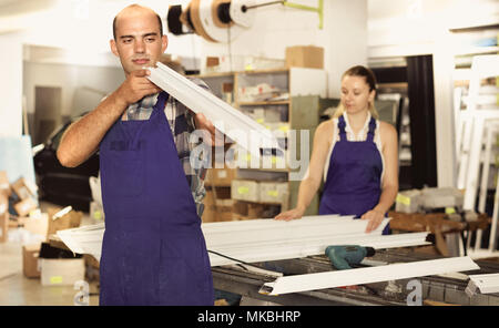 Serious  man working in workshop for assembling plastic windows, checking quality Stock Photo