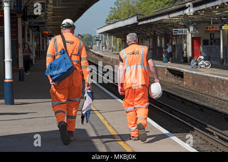 Permanent Way engineers dressed in reflective clothing at Basingstoke Station, Hampshire, England UK. Lookout man holding warning flags. Stock Photo