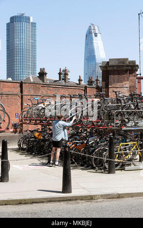 Waterloo Station, London UK. 2018. Two tier parking for customers to park their cycles. A male customer parking his bike Stock Photo