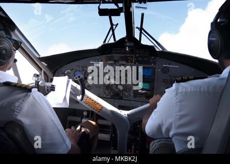 View of the cockpit of a small airplane flying in the sky. Team of pilots on plane, crew touching equipment and commands on dashboard Stock Photo