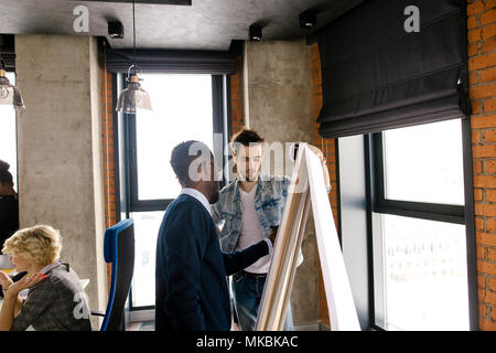 closeup image of afro businessman putting his ideas on the board with flipping sheet . white scheme on the flipchart while business meeting Stock Photo