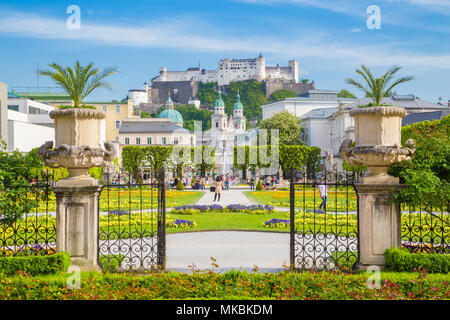 Classic view of famous Mirabell Gardens with the old historic Fortress Hohensalzburg in the background on a beautiful sunny day with blue sky and clou Stock Photo