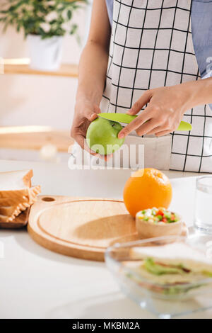Hands of a woman is making school lunch box in the red color. It is more interesting for children. Caucasian female preparing food (fruits and vegetab Stock Photo