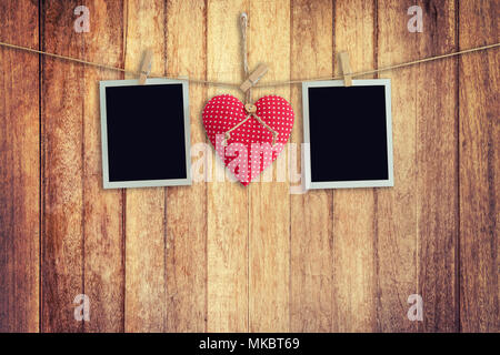 Blank instant photos and red heart hanging on wooden background. Stock Photo