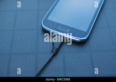 Use of renewable energy - Mobile Phone Chargers on grass in nature with Sun Stock Photo