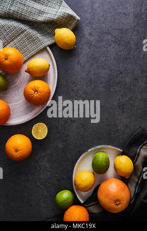 Top view of fresh ripe citruses. Lemons, limes, oranges and grapefruits on dark concrete background. Flat lay with copy space. Stock Photo