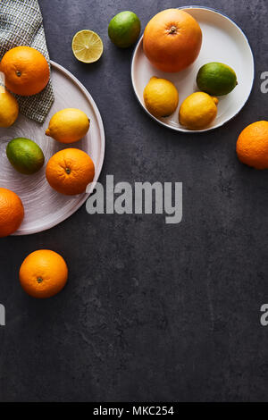 Top view of fresh ripe citruses. Lemons, limes, oranges and grapefruits on dark concrete background. Flat lay with copy space. Stock Photo