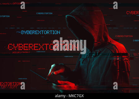 Cyberextortion concept with faceless hooded male person using tablet computer, low key red and blue lit image and digital glitch effect Stock Photo