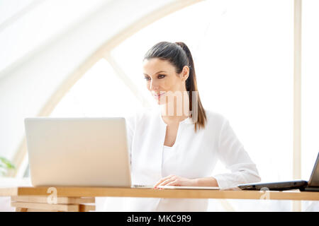 Portrait of attractive young sales assistant businesswoman using laptop at the office. Stock Photo