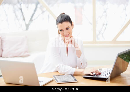 Portrait of thinking young businesswoman using laptops while working on new project at the office. Stock Photo