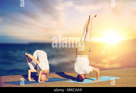 couple doing yoga headstand outdoors Stock Photo