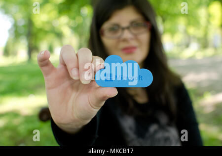 Nis, Serbia, April 24, 2018:  woman on blurred background reach out  holding Microsoft Windows OneDrive icon, outdoor in park Stock Photo