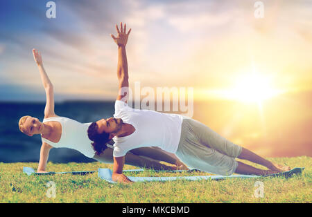 couple doing yoga and side plank outdoors Stock Photo