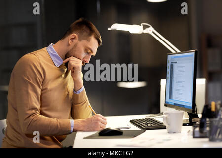 man with notepad working on code at night office Stock Photo