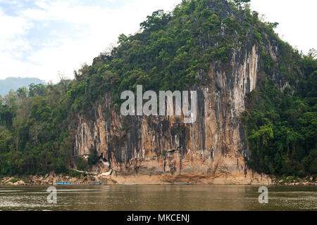 View of the Mekong River and limestone cliff where the famous Pak Ou Caves are set. They are located near Luang Prabang in Laos. Stock Photo