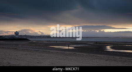 Liverpool, England, UK - November 12, 2016: The sun sets behind Antony Gormley's 'Another Place' sculptures on Crosby Beach, with the mountains of Sno Stock Photo