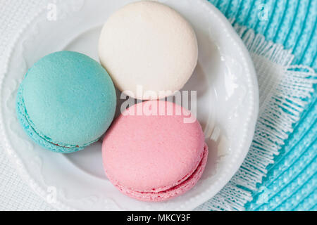 Three macaroons of different colors and different tastes in a white plate, top view. Romantic morning, gift for beloved. Breakfast on Valentin's, Mothers, Women's day Stock Photo