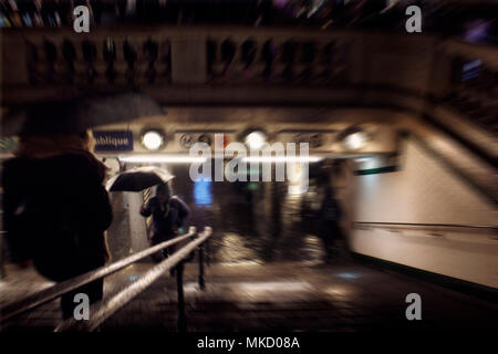 Blurry motion image of people at the entrance of a famous subway station called Republique (meaning Republic in French) at night in Paris. Stock Photo