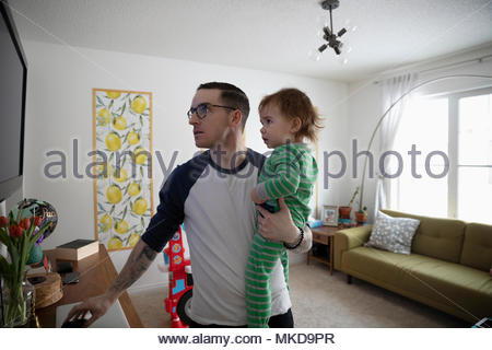 Father holding baby son, watching TV in living room Father holding baby son, watching TV in living room