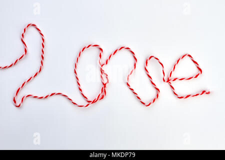 Word love from thread on white background. Inscription love from red and white woolen thread. Valentines Day and love concept. Stock Photo