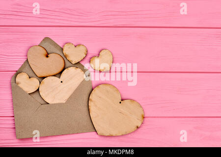 Plywood hearts, envlope and copy space. Blank wooden hearts with hole and envelope on colorful wooden background, text space. Stock Photo