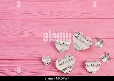 Paper hearts with notes and copy space. Heart shaped paper figures with music notes on wooden background. Stock Photo
