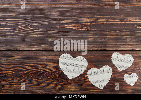 Paper hearts and copy space. White paper hearts with music notes on dark wooden background, text space. Stock Photo