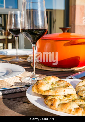 https://l450v.alamy.com/450v/mke77d/outdoor-table-set-with-red-wine-in-glasses-and-orange-le-creuset-casserole-pot-woith-naan-bread-on-sunny-evening-scotland-uk-mke77d.jpg