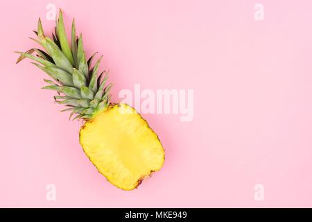 Half cut juicy pineapple on a pastel pink background. Minimal summer concept. Stock Photo