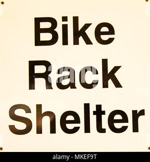 Black and white bike rack sign close up in busy urban shopping area ...
