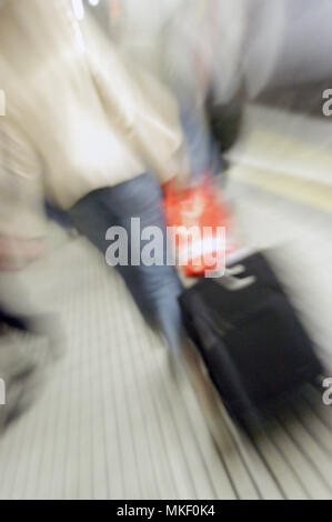 Tube commuters time, young woman pulling suitcase through london underground Stock Photo
