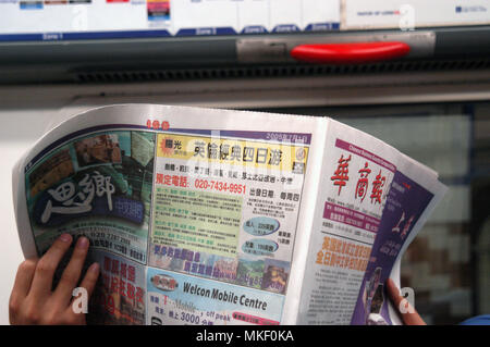 Tube commuters time, man commuting and reading asian newspaper on the tube Stock Photo