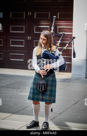 Young girl bagpiper playing bagpipes on street outside in city Glasgow, Scotland iconic Scottish sight piper sounds in kilt Stock Photo