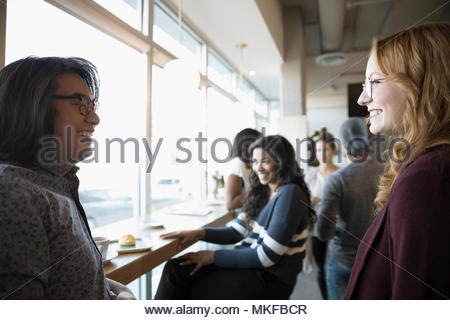 Smiling young friends talking in cafe