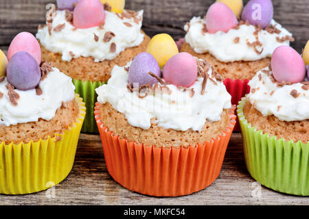 Close up of little easter cupcakes with easter eggs and frosting on wood background Stock Photo