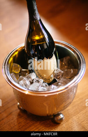 Champagne bottle in steel bucket with ice on wooden table close up Stock Photo