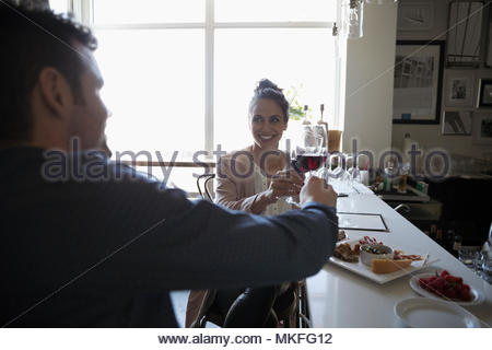 Young couple on date toasting red wine glasses in bar