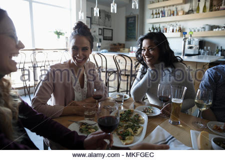 Young women friends enjoying happy hour at bar, drinking wine