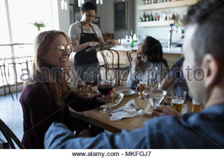 Smiling young woman enjoying happy hour at bar, drinking wine
