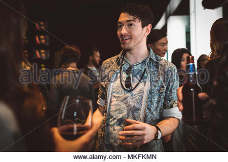 Young male millennial drinking and talking with friends in bar